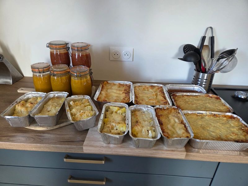 Barquettes de gratin alignées sur un plan de travail avec des bocaux de soupe